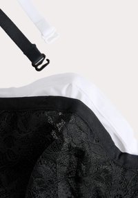 Encaje negro y superposición de tela con tirantes blancos y negros. Patrón floral texturizado sobre un fondo suave en negro y blanco.