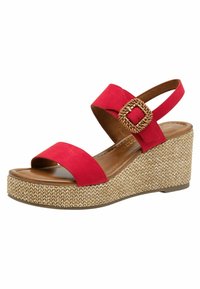 Sandale compensée en daim rouge avec une large lanière ornée d'une boucle tressée et une semelle plateforme beige texturée. Semelle intérieure lisse marron.