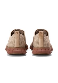 Sneakers in rete beige con un design a profilo basso, suola in gomma e dettagli testurizzati sulla tomaia. Presentano un'accenno di logo sul tallone.