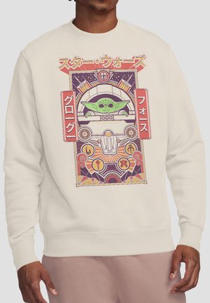 Man wearing beige sweatshirt featuring Grogu (Baby Yoda) from Star Wars in a colorful, retro-style pinball machine design with Japanese text.