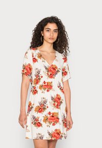 Vestido floral em tecido leve com fundo branco, apresentando grandes rosas vermelhas e laranjas, mangas curtas e decote em V.