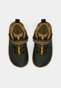 Une paire de baskets pour enfants vertes et noires avec des lacets rayés jaunes, des bandes Velcro brunes et des intérieurs rembourrés couleur tan, montrée de dessus.