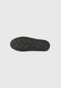 Suela de zapato de goma negra con un patrón texturizado en zigzag, diseño plano y ligeras estrías en los bordes. Tamaño marcado como 37.