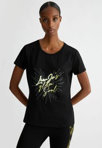 T-shirt nera a maniche corte realizzata in cotone, con una grafica multicolore che presenta il testo "Lun Jo's glam Soul" e un design a esplosione di stelle.