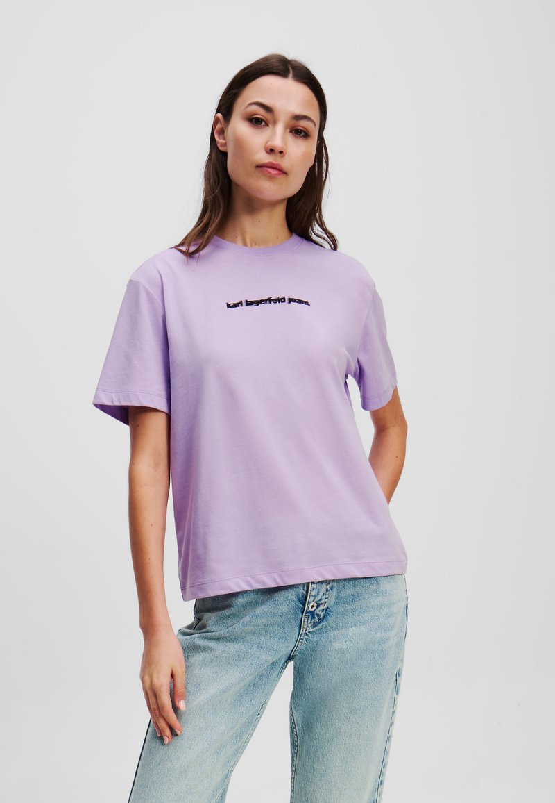 Levandulové bavlněné tričko s krátkým rukávem a klasickým výstřihem, s černým nápisem "karl lagerfeld jeans" na přední straně.