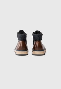 Brune lær ankle boots med en mørk stofkrave, sideskydere og teksturerede gummisåler. Syntetiske detaljer og en kontrasterende mellemsål.
