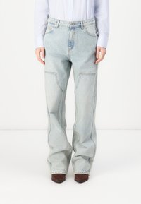 Jeans de mezclilla de color azul claro con un corte holgado, que cuentan con bolsillos frontales y una cremallera. El material tiene una textura desgastada, con ligeras variaciones de color.