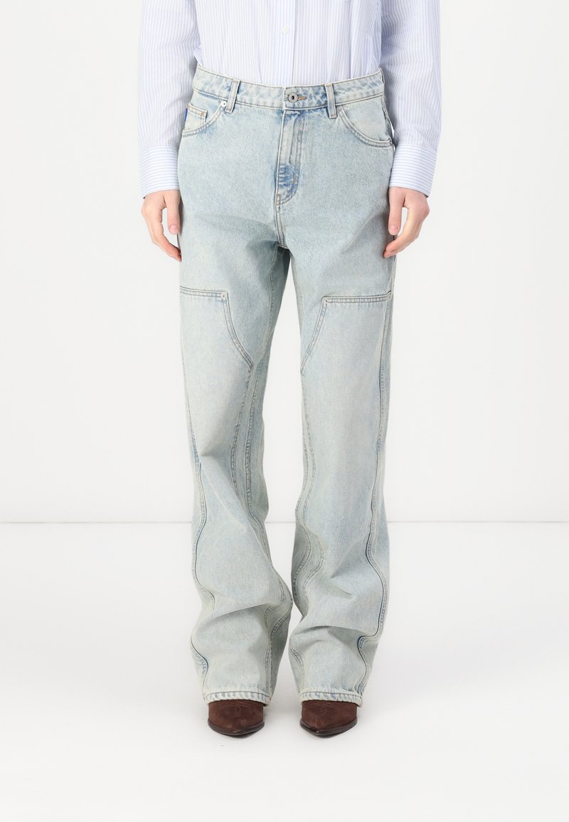 Jeans de mezclilla de color azul claro con un corte holgado, que cuentan con bolsillos frontales y una cremallera. El material tiene una textura desgastada, con ligeras variaciones de color.
