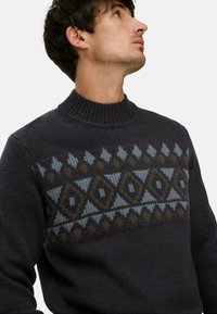 Dunkelgrauer gestrickter Pullover mit einem gerippten Rollkragen und geometrischen Mustern in Blau und Braun über der Brust. Weiche Textur.