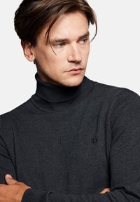 Ciemnoszary sweter z golfem o prążkowanej fakturze i dopasowanym kroju, z małym logo na lewej piersi.