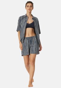 Marinblå och krämrandig pyjamasuppsättning med kortärmad knäppskjorta och shorts med elastisk midja, tillverkad av lättviktsmaterial.