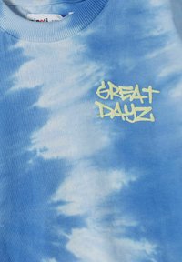 Mėlynos spalvos tamsintas džemperis su raukšlėta apykakle ir „GREAT DAYZ“ šviesiai geltonos spalvos grafiti stiliaus tekstu priekyje.