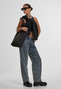 Musthave musta katkisega topp, kogumise detailiga, ülerahuldatud hallid denim teksad, massiivsed mustad platvormisaapad ja tikitud must zangott.