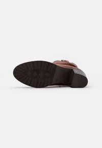 Botte de cheville en cuir marron avec un bout carré, fermeture éclair latérale et un petit talon empilé. La semelle texturée présente un grip à motif pour une meilleure adhérence.