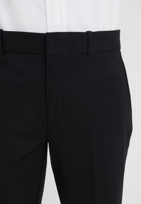 Svarta skräddarsydda byxor med en slät yta, med flat front, bältesöglor och en klassisk passform för en strömlinjeformad siluett.