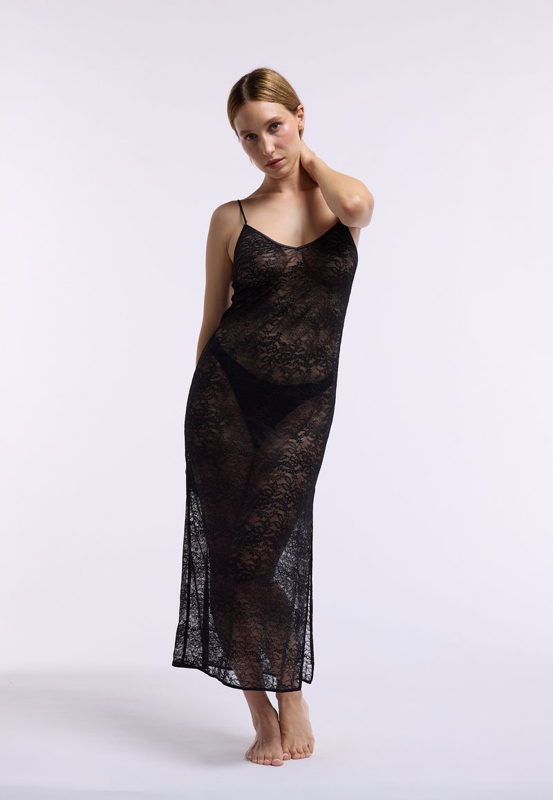 Vestaglia nera in pizzo con spalline regolabili, caratterizzata da motivi floreali e una texture trasparente. Design lungo e fluente fino al polpaccio.