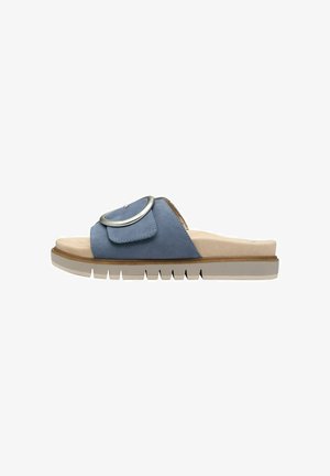 Blå ruskinds slide sandal med en rund metalaccent, beige indersål og en chunky hvid ydersål med teksturerede riller.