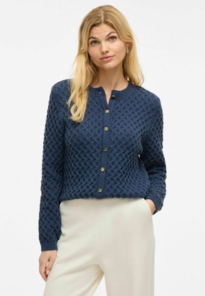 Navy blue knitted cardigan with diamond pattern, round neckline, and gold buttons. Designed with a fitted waist and long sleeves.