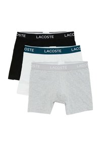 Three pairs of men's boxers in black, white, and grey. Each features an elastic waistband with "LACOSTE" lettering in contrasting colors.