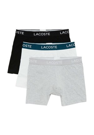 Tre par herreboxershorts i sort, hvid og grå. Hver enkelt har et elastisk bælte med "LACOSTE"-skrift i kontrastfarver.