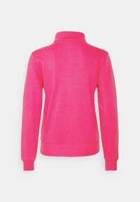 Pullover in pile di colore rosa brillante con colletto alto, maniche lunghe, polsini a costine e orlo dritto. Texture liscia e dettagli minimi.