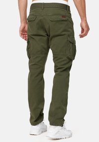 Oliivinvihreät kestävasta kankaasta tehdyt cargo-housut, joissa on useita sivutaskuja ja suora lahjemalli. Yhdistetty valkoisiin tennareihin.