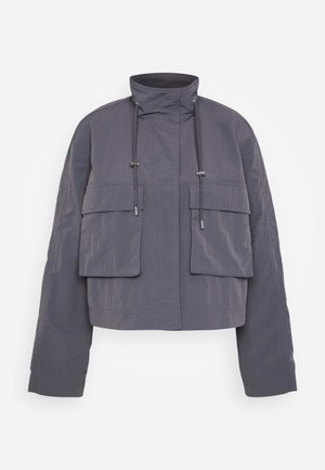 Cropped jacket in dark gray fabric, featuring two front pockets, a high collar, and drawstrings for adjustments. Smooth texture and relaxed fit.