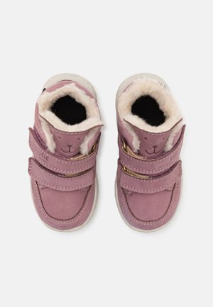 Rosa Wildlederschuhe mit weißem Kunstpelzfutter, doppelten Klettverschlüssen, runder Zehenform und einem Tiergesicht-Detail auf der Zunge.