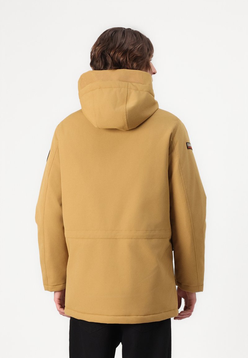 Chaqueta aislante amarilla con capucha, de corte relajado y textura suave. Incluye un pequeño logo en el hombro izquierdo.