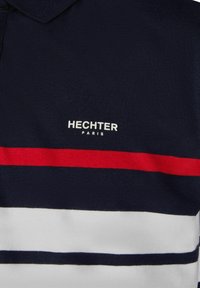 Marineblauw polo shirt met horizontale strepen in rood, wit en marineblauw. Het logo "HECHTER PARIS" is in het wit geborduurd aan de linkerkant.