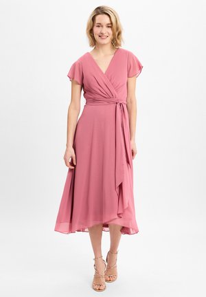 Roze wikkeljurk met korte fluttermouwen, een ceintuur in de taille en een vloeiende zoom. Gemaakt van lichte stof met een soepele textuur.