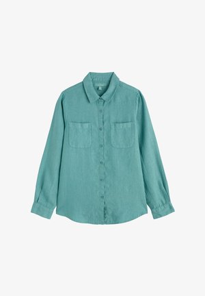 Tumši zaļa garroku kreklā ar apkakli un divām krūšu kabatām, izklāts uz balta fona.