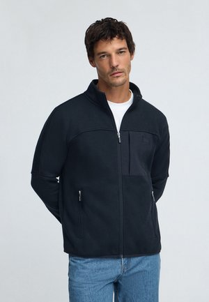 Schwarze Fleecejacke mit hohem Kragen, Frontreißverschluss und Brusttasche. Verfügt über zwei Seitentaschen und eine glatte Textur.