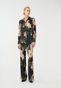 Set di camicia e pantaloni in seta nera con motivi floreali beige. Presenta una camicia con colletto e pantaloni a gamba larga, con una texture liscia e una vestibilità su misura.