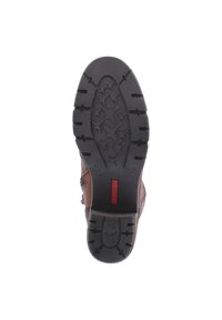 Suela de bota de cuero marrón con una textura de goma negra y un dibujo de estrellas, y un acento de logotipo rojo. Tamaño 36 indicado.
