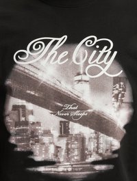 Svart bomull T-skjorte med et grafisk trykk av en bylandskap, med "The City" i kursiv og "That Never Sleeps" nedenfor i hvit tekst.