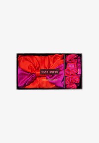 Conjunto de accesorios para el cabello de seda en rojo y rosa, que incluye un gran scrunchie y scrunchies más pequeños a rayas. Presentado en una caja con detalles de marca mínimos.