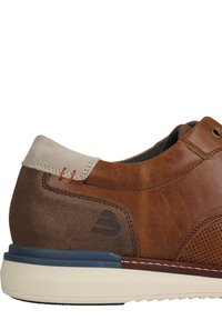 Scarpa in pelle marrone con colletto in suede grigio chiaro, texture perforata, cuciture arancioni e suola beige. Presenta un logo grigio di lato.