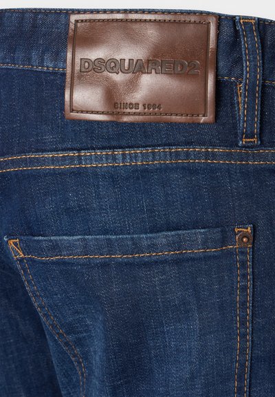 Τζιν παντελόνι με σκούρο πλύσιμο, που διαθέτει καφέ δερμάτινο λογότυπο με την ένδειξη «DSQUARED2», κίτρινη ραφή και λεπτομέρεια πίσω τσέπης.