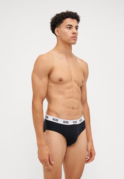 Slip neri con una fascia bianca con il logo GCDS. Tessuto liscio con una vestibilità aderente, caratterizzato da un design classico e dettagli minimi.