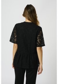 Top in pizzo nero con maniche corte e orlo a peplo. Motivo floreale intricato, superficie strutturata e scollatura rotonda.