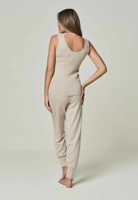 Cremfarbener Tanktop mit weitem Ausschnitt, kombiniert mit passenden tapered Jogginghosen mit elastischen Bündchen. Weicher, strukturierter Stoff, lässiges Design.