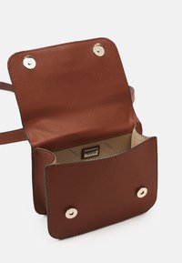 Bruine gestructureerde leren crossbodytas met gouden hardware. Voorzien van een magnetische drukknoopsluiting en een binnenlabel. Open ontwerp.