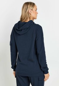 Felpa con cappuccio di un blu navy scuro, con texture a coste, vestibilità comoda e cappuccio. Presenta maniche lunghe e una tasca laterale sul braccio sinistro.