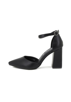 Scarpa nera con tacco alto e punta affusolata, realizzata in pelle liscia, con un robusto tacco a blocco e una sottile cinghia alla caviglia con una fibbia metallica.
