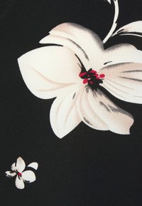 Blommönstrad tyg med stora vita blommor och subtila grå inslag samt en liten blomma, mot en enhetlig svart bakgrund.