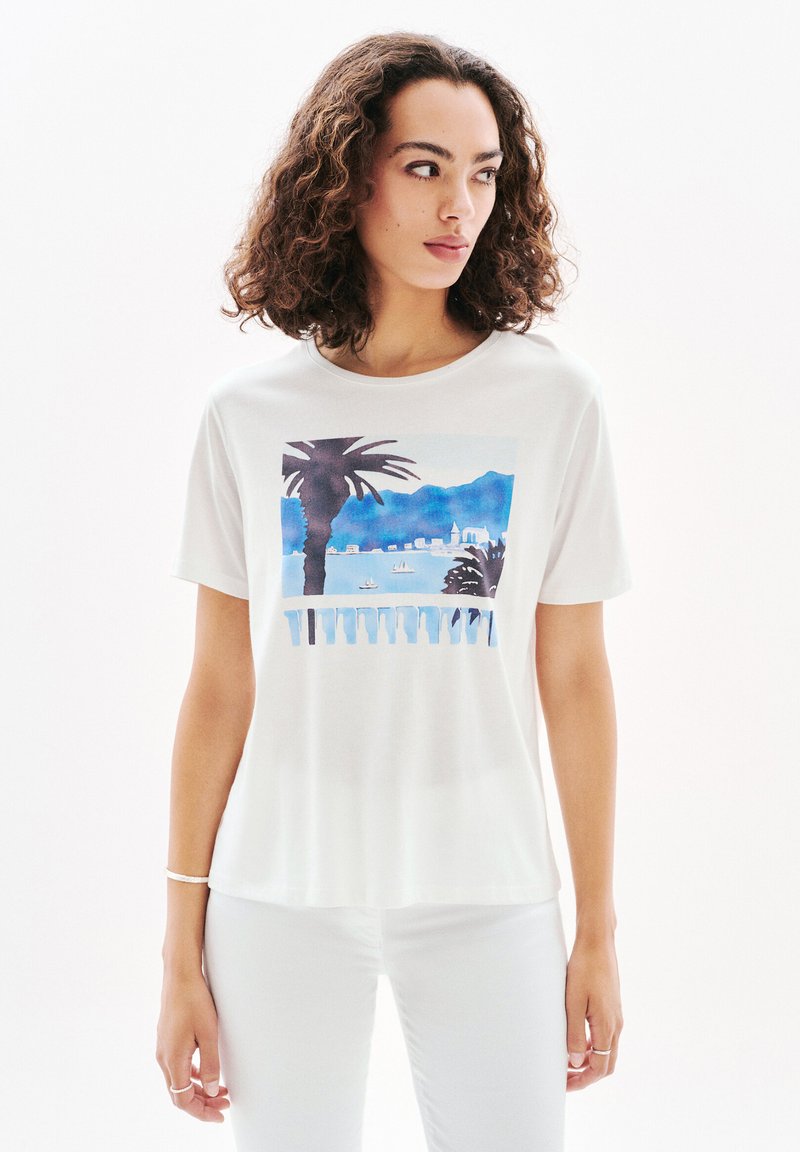 Valkoinen puuvillapaita, jossa on värikäs painettu kuvio palmupuista ja merimaisemasta sinisissä sävyissä. Lyhyet hihat ja pyöreä kaula-aukko.