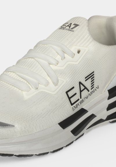 Бял маратонка EA7 Emporio Armani с връзки и черни акценти на подметката, показващи логото на марката отстрани и на езика.