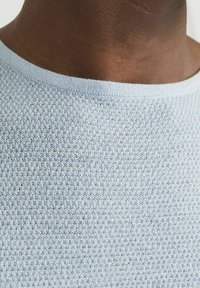 Suéter de punto azul claro con un patrón texturizado, que presenta un cuello redondo y un ribete acanalado. La tela parece suave y transpirable.
