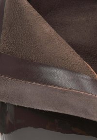 Brązowe zamszowe buty i błyszczące ciemne skórzane buty o gładkiej powierzchni, przeszywanym brzegu i miękkim wnętrzu. Brak wyraźnych wzorów lub szczegółów sprzętowych.